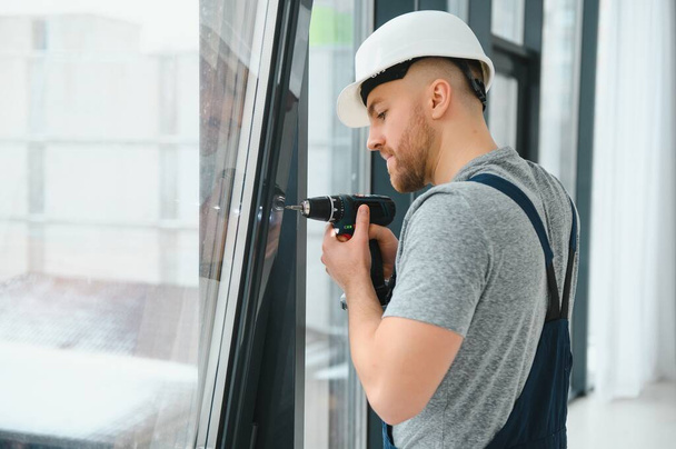 service man installing window with screwdriver - Photo, image
