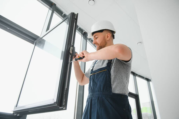 handsome young man installing bay window in new house construction site - 写真・画像