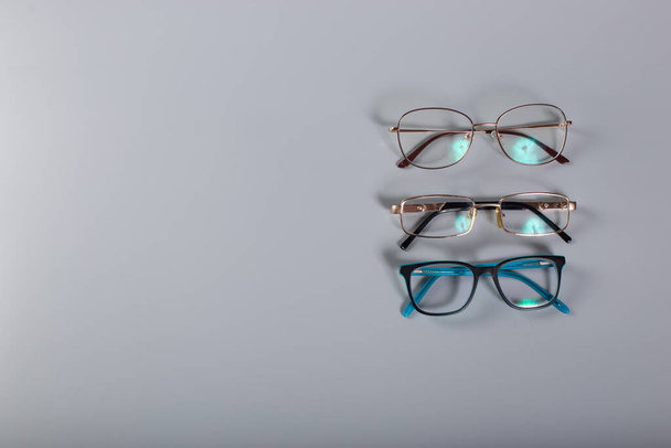 Three pairs of eyeglasses close up on grey background with copy space. - Zdjęcie, obraz