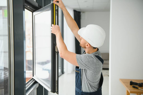 handsome young man installing bay window in new house construction site - Foto, Bild