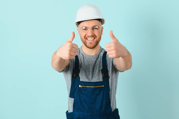Craftsmen or electrician man over isolated blue background giving a thumbs up gesture - Фото, изображение