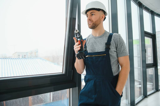 handsome young man installing bay window in new house construction site - Фото, зображення