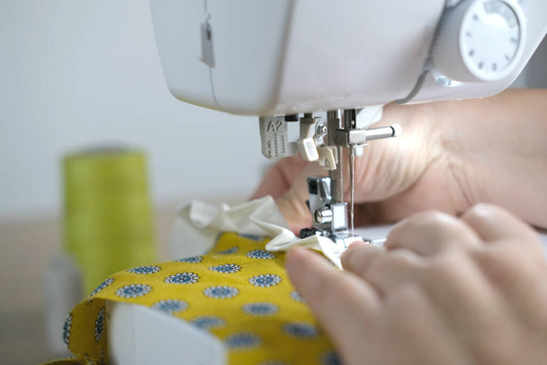 close-up of female hands perform work on a white sewing electric computer machine, stitches appear step by step on the fabric, concept of tailoring, women's hobby, modern needlework - Fotó, kép