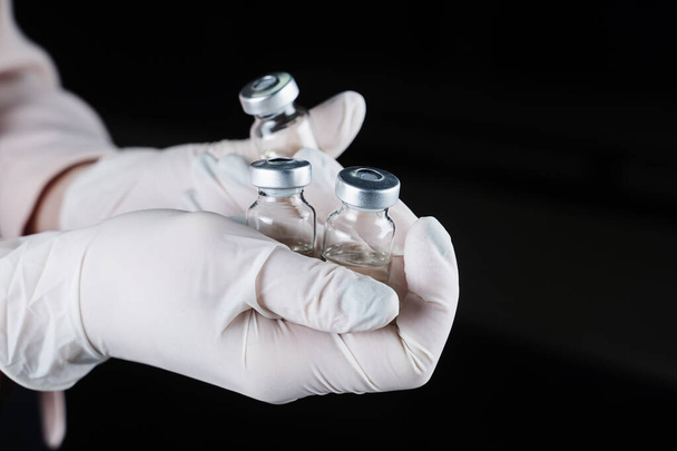 3 Coronavirus-Booster-Impfstoffe in den Händen in medizinischen Handschuhen. Covid-19-Impfung - Foto, Bild