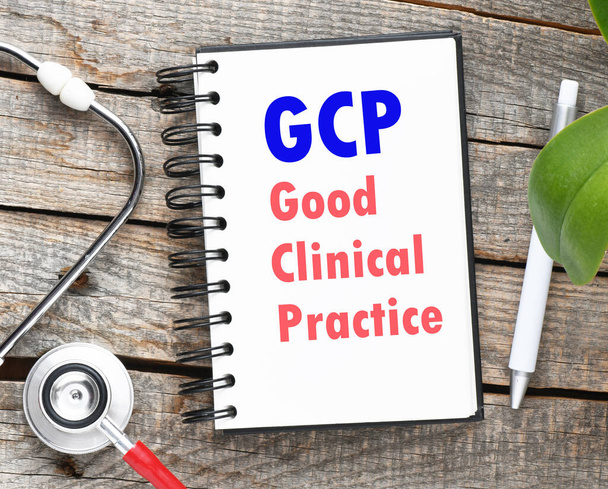 Palabras GCP (Good Clinical Practice) escritas en un cuaderno sobre una mesa de madera. Concepto médico. - Foto, imagen