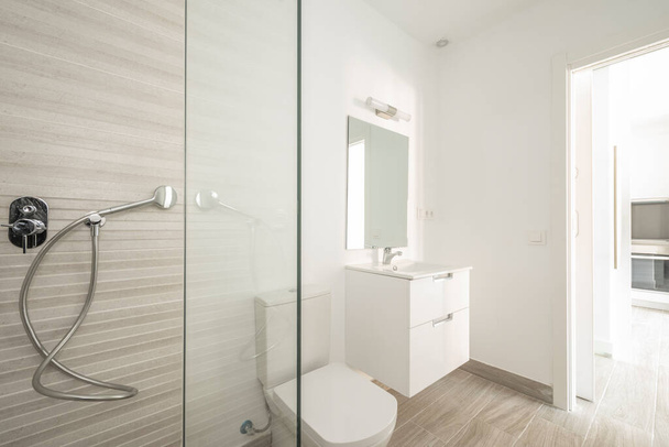 Toilet with shower and white sink, rectangular mirror in short-term rental apartment - Fotó, kép