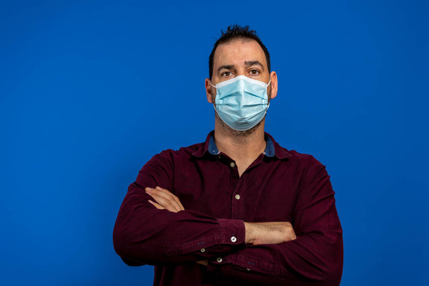 Портрет уверенного позитивного парня крест руки готовы остановить ковид-19 инфекция распространяется носить фиолетовую одежду медицинскую маску изолированы на ярко-голубой цвет фона - Фото, изображение
