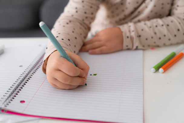 Portrait of cute preschooler child girl drawing with pencils at home while sitting in front of the camera with attentive face. Stock photo - Φωτογραφία, εικόνα