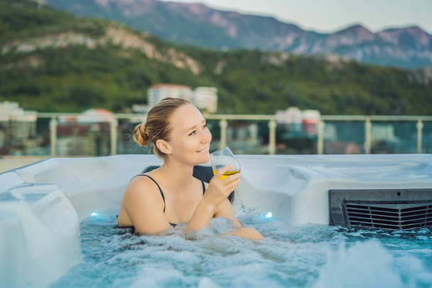 Portrait of young carefree happy smiling woman relaxing at hot tub during enjoying happy traveling moment vacation life against the background of green big mountains - 写真・画像