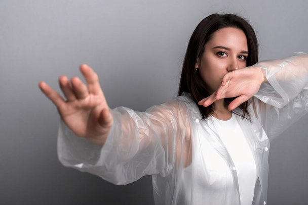 Young woman covers her mouth with one hand and puts her other hand in front, blurred front focus - Photo, Image