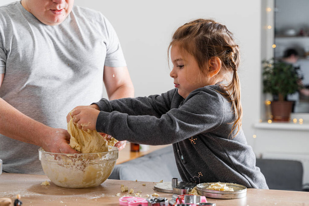 Father feeling playful with his caucasian little daughter, while preparing homemade dough for tasty cookies. Father and his child spending time at home  - Fotó, kép