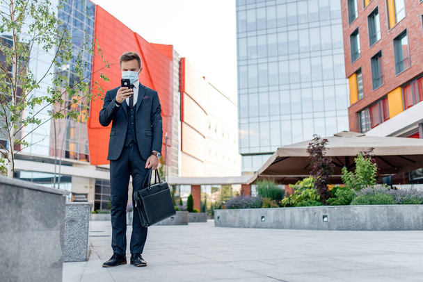 Young man in formal wear using smartphone in city, - Фото, изображение