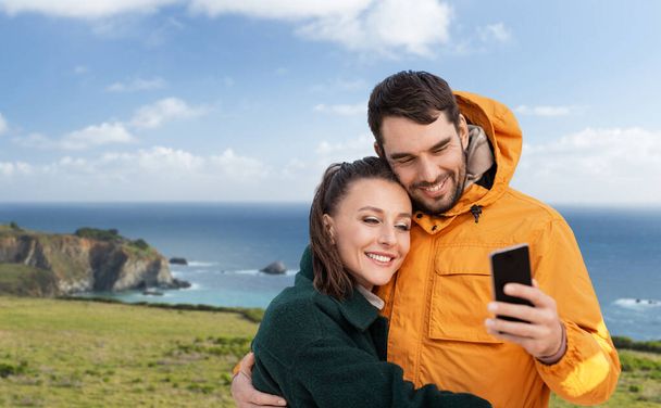 couple with smartphone over coast in california - Фото, зображення