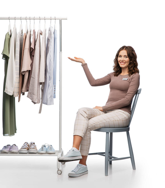 happy female shop assistant with clothes on hanger - Fotoğraf, Görsel