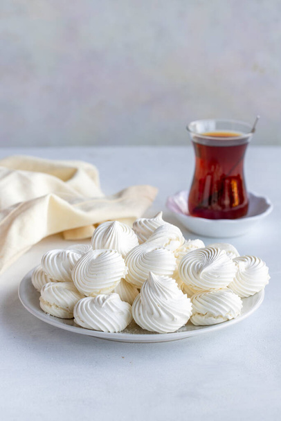 Pequeños merengues blancos en un plato blanco. Macro disparó. Vista vertical - Foto, Imagen
