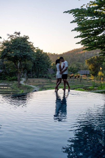 pareja hombre y mujer viendo la puesta de sol en un borde de una piscina con vistas a las montañas y arrozales del norte de Tailandia Mae Hong Son - Foto, imagen