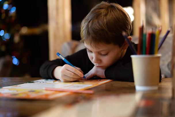 mignon petit garçon dessin avec des crayons de couleur assis à la table dans le restaurant. Image avec mise au point sélective - Photo, image