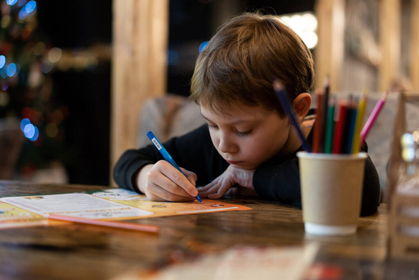 Lokantada masada oturan renkli kalemlerle resim yapan sevimli küçük çocuk. Seçici odaklı resim - Fotoğraf, Görsel