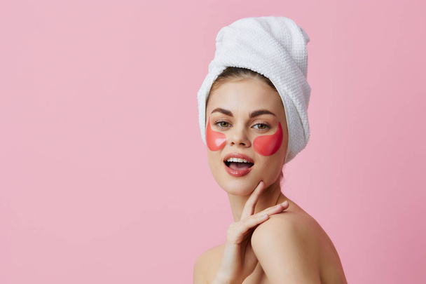 hermosa mujer parches de color rosa en la cara con una toalla en la cabeza fondo aislado - Foto, Imagen