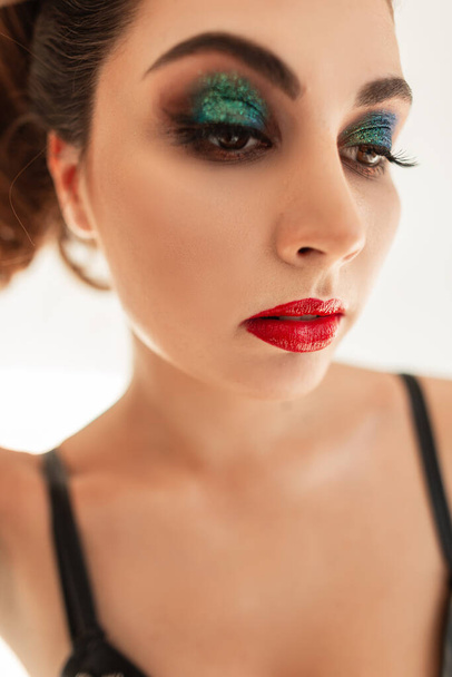 Portrait coloré glamour d'une belle jeune femme avec maquillage, lèvres rouges et fards à paupières verts sur fond blanc en studio - Photo, image