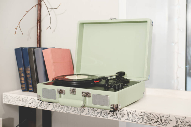 retro stylu domu odtwarzacza płyt winylowych lub gramofonu. przenośne urządzenie do słuchania płyt LP. muzyka retro. klasyczne książki na półce - Zdjęcie, obraz