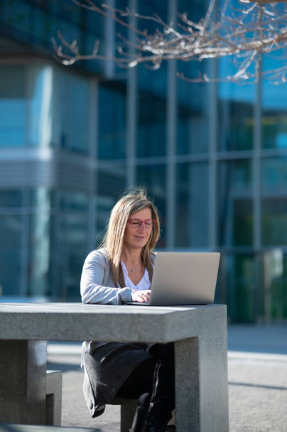 Kobieta z laptopem na zewnątrz w przestrzeni biurowej, z przestrzenią do kopiowania - Zdjęcie, obraz