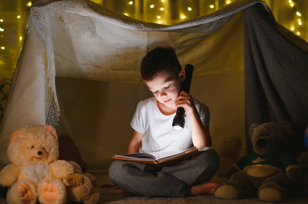 the child is reading a book with a flashlight - Zdjęcie, obraz