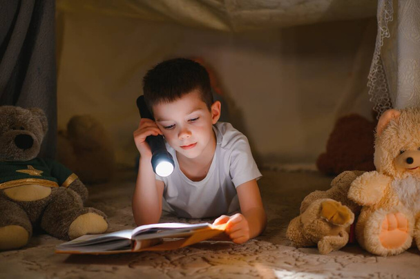 Two little child play at home in the evening to build a camping tent to read books with a flashlight and sleep inside. Concept of: game, magic, creativity, alarm systems - Φωτογραφία, εικόνα