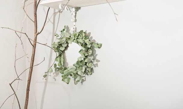 eucaliptus branch wreath hanging on a wall, spring decor in a rustic style home. seasonal decoration for spring holidays. copy space - Photo, Image