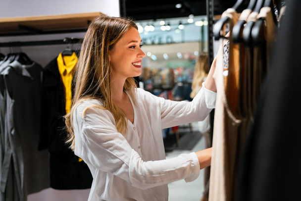 Egy gyönyörű fiatal nő portréja, aki a ruhaboltban vásárol. Az emberek fogyasztói eladásainak koncepciója. - Fotó, kép