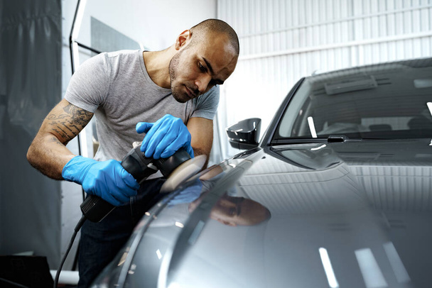 Car detailing. Male hands with orbital polisher in auto repair shop - Фото, изображение