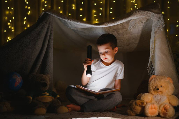 the child is reading a book with a flashlight - Zdjęcie, obraz