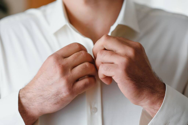 A man fastens buttons on his shirt. - Фото, зображення