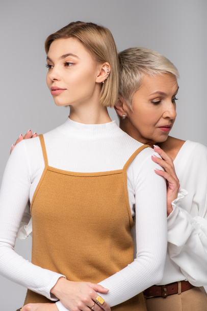 middle aged mother embracing young daughter looking away isolated on grey - Foto, imagen