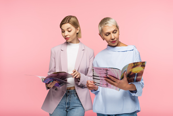 érett anya és fiatal lánya olvasás magazinok elszigetelt rózsaszín - Fotó, kép
