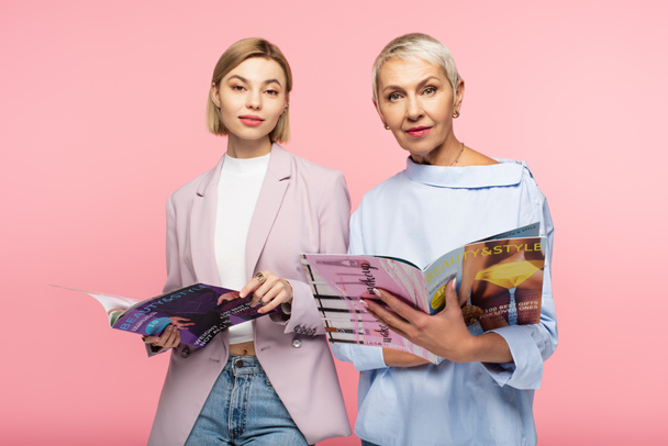 reife Mutter und kleine Tochter halten Zeitschriften isoliert auf rosa - Foto, Bild