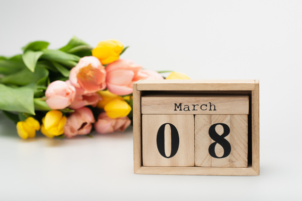 wooden cubes with 8 march lettering near blurred tulips on white - Foto, afbeelding