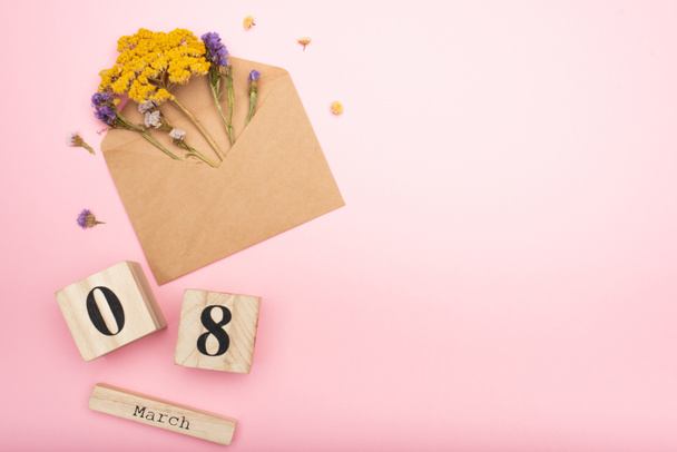 top view of dry flowers in craft envelope with dried flowers near wooden calendar cubes with 8 march on pink  - Photo, Image