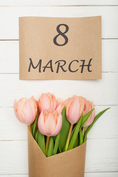 верхний вид бумаги ремесла с 8 марта рядом букет тюльпанов на белой деревянной поверхности - Фото, изображение