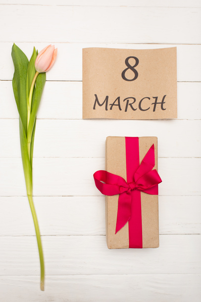 vista superior de papel artesanal con 8 marzo cerca de tulipán rosa cerca presente en la superficie de madera blanca - Foto, imagen