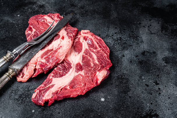 Čerstvé mramorové maso Steaky s nožem na maso a vidličkou, steak z hovězího žebra. Černé pozadí. Horní pohled. Kopírovat prostor - Fotografie, Obrázek