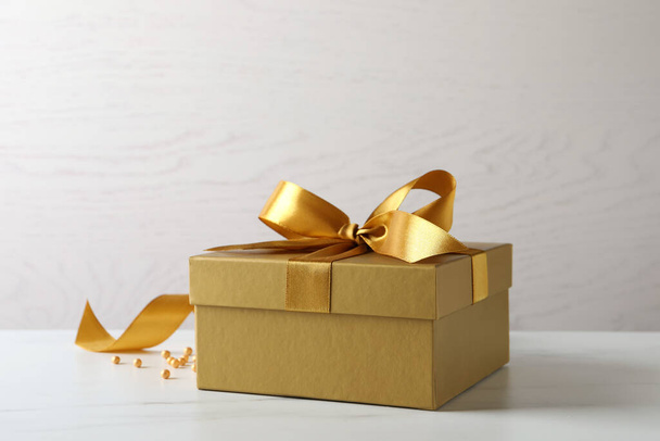 Beautiful golden gift box and decor on white table - Foto, Imagen