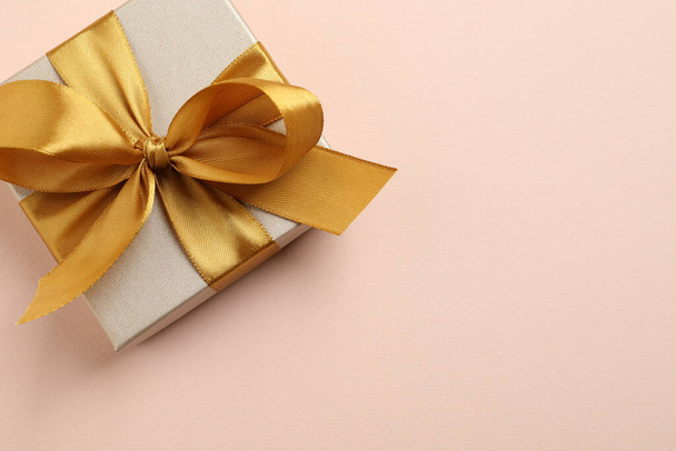 Beautiful gift box with golden bow on pink background, top view. Space for text - Valokuva, kuva