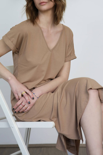 Frau in lässigem beigem Stretch-Baumwoll-Midi-Kleid. T-Shirt-Kleid aus Bio-Baumwolle. Studioaufnahme. - Foto, Bild