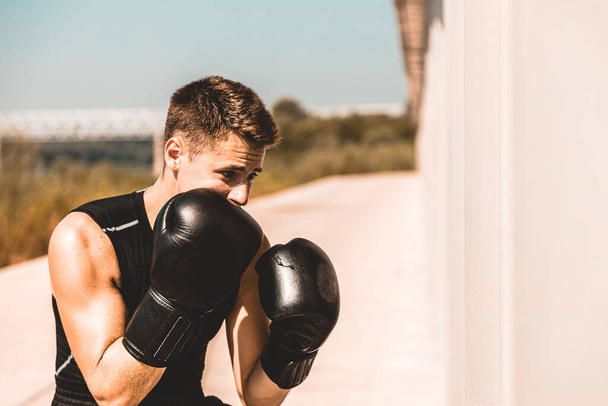 Man exercising and fighting in outside, boxer in gloves. male boxer portrait - Foto, imagen