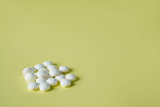 Medicine yellow background from bunch white pills, macro. Drug production backdrop, closeup. Tablet of vitamins for health and pain. Medical concept. - Φωτογραφία, εικόνα