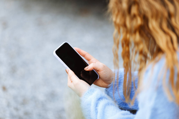 Primer plano de las manos de las mujeres en suéter azul sosteniendo y utilizando el teléfono inteligente móvil - Foto, imagen