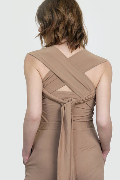 Serie von Fotos von weiblichen Model trägt beige Multi-Wear-Wrap-Around-Tank-Top aus Bio-Baumwolle und Basishose. - Foto, Bild