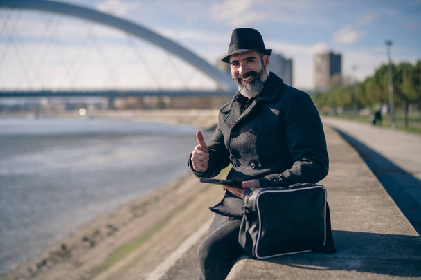 Businessman è seduto all'aperto in città e utilizzando tablet digitale. - Foto, immagini