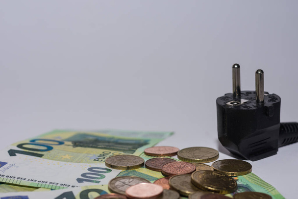 energieverbruik en stijging van de elektriciteitsprijzen eurobiljetten en -muntstukken met stekker op grijze achtergrond macro-economisch beeld - Foto, afbeelding